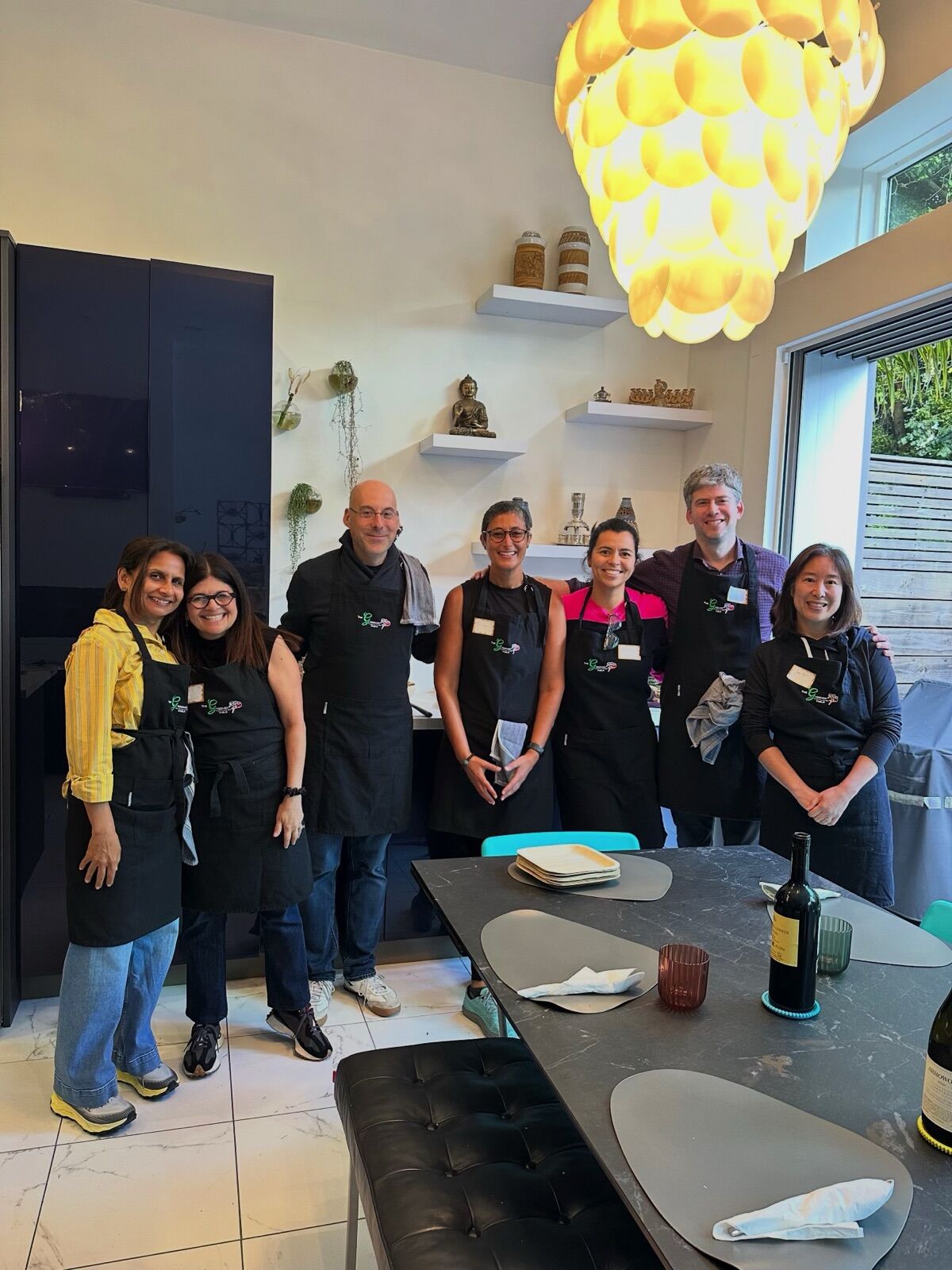 A Crew gathered in the kitchen under a glowing pendant light