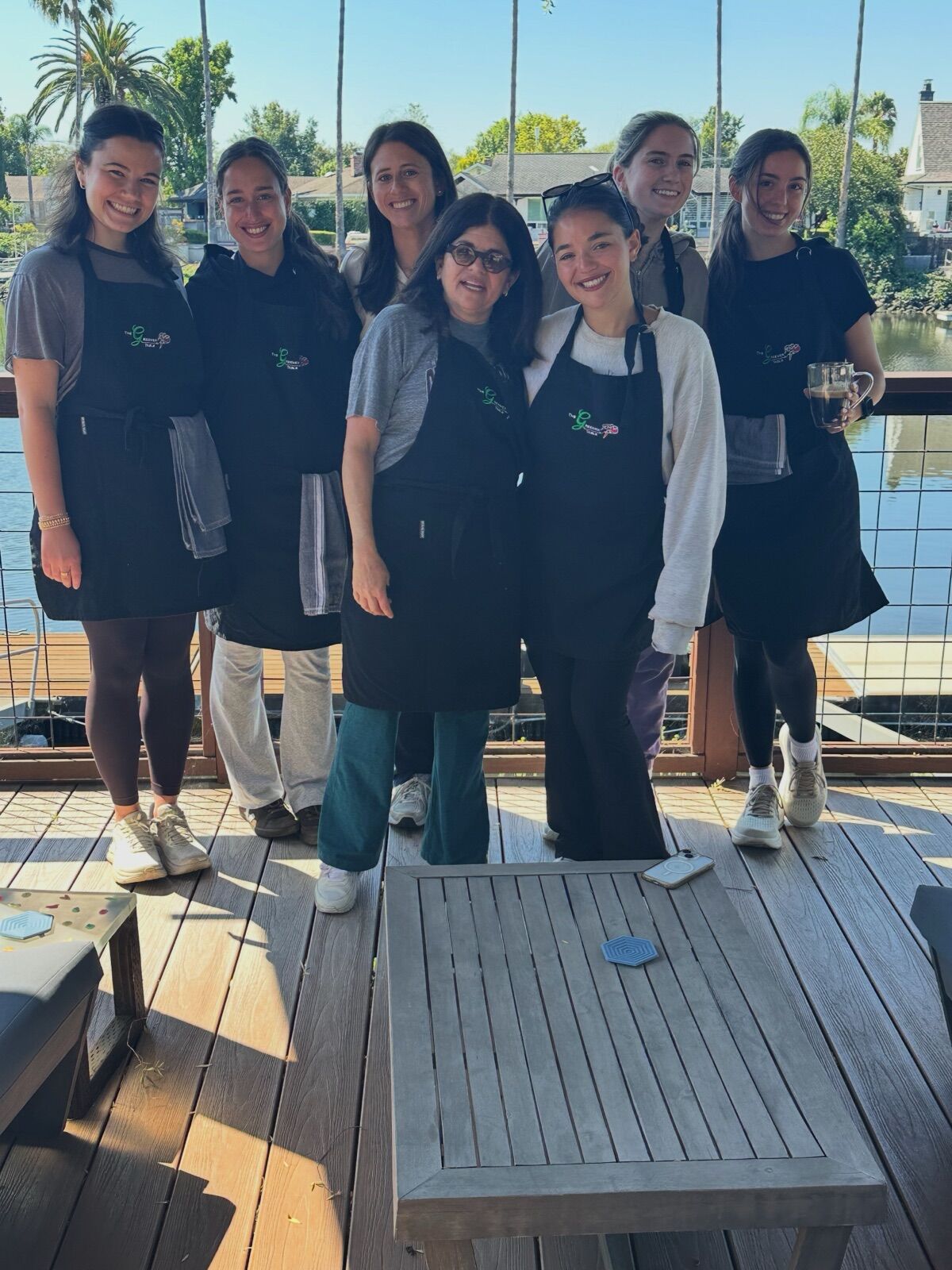 A Crew in matching aprons on a sunny deck by the water