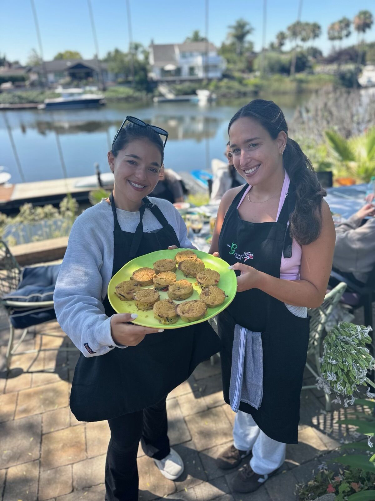 Two guests holding a plate of pupusas outside by the water
