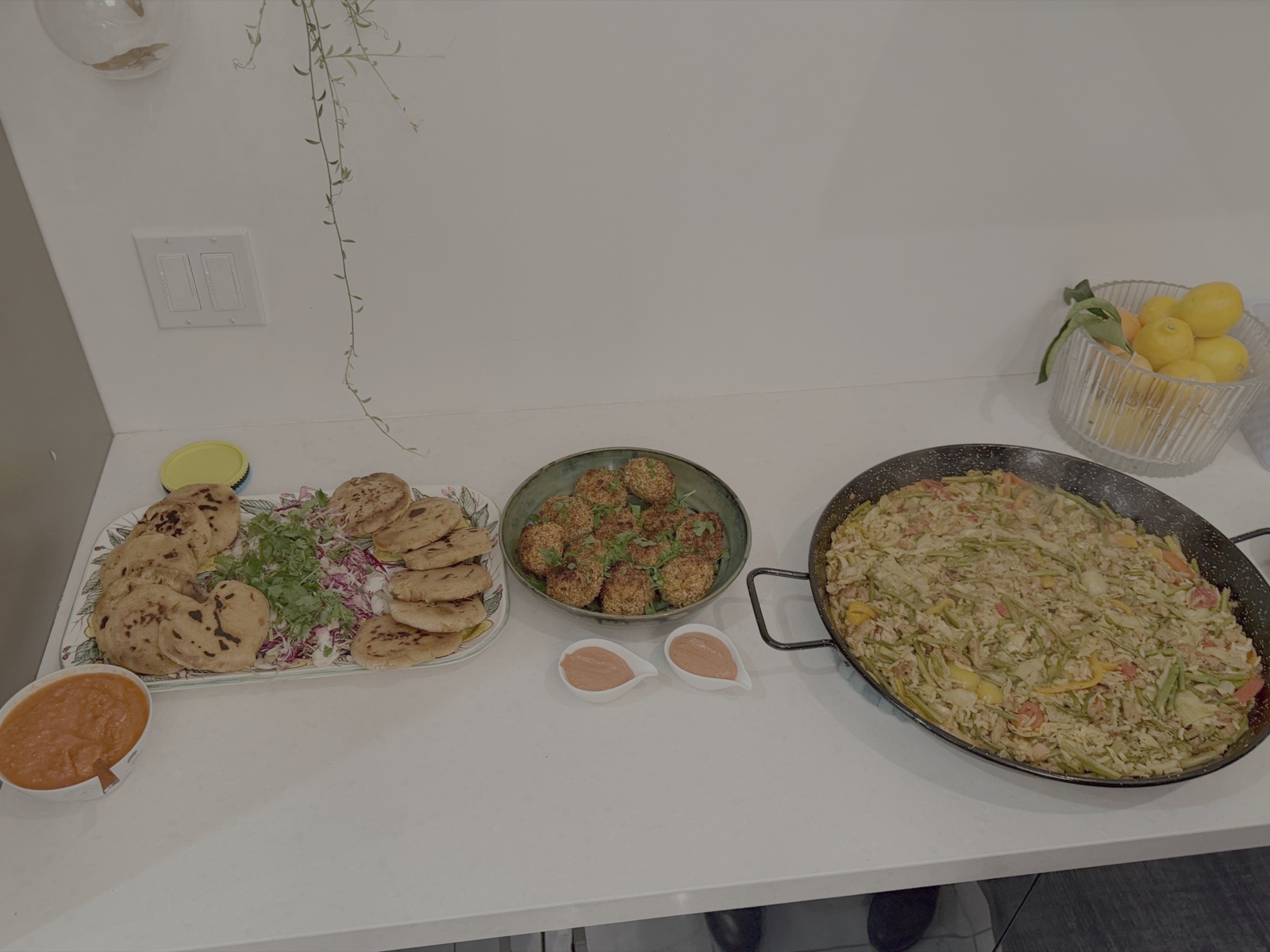 Arancini, dipping sauce and paella laid out on the counter